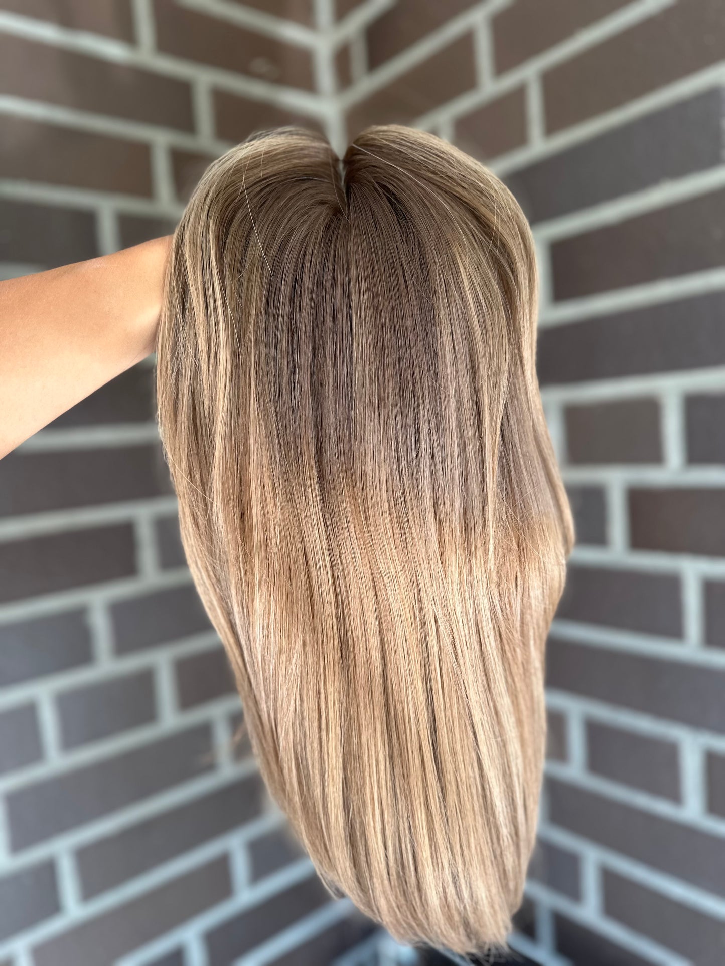 Bild zeigt blondes Echthaarteil, das frontal ins Bild gehalten wird. Bild dient der Produktpräsentation eines Artikels in der Kategorie Topper/Perücken.