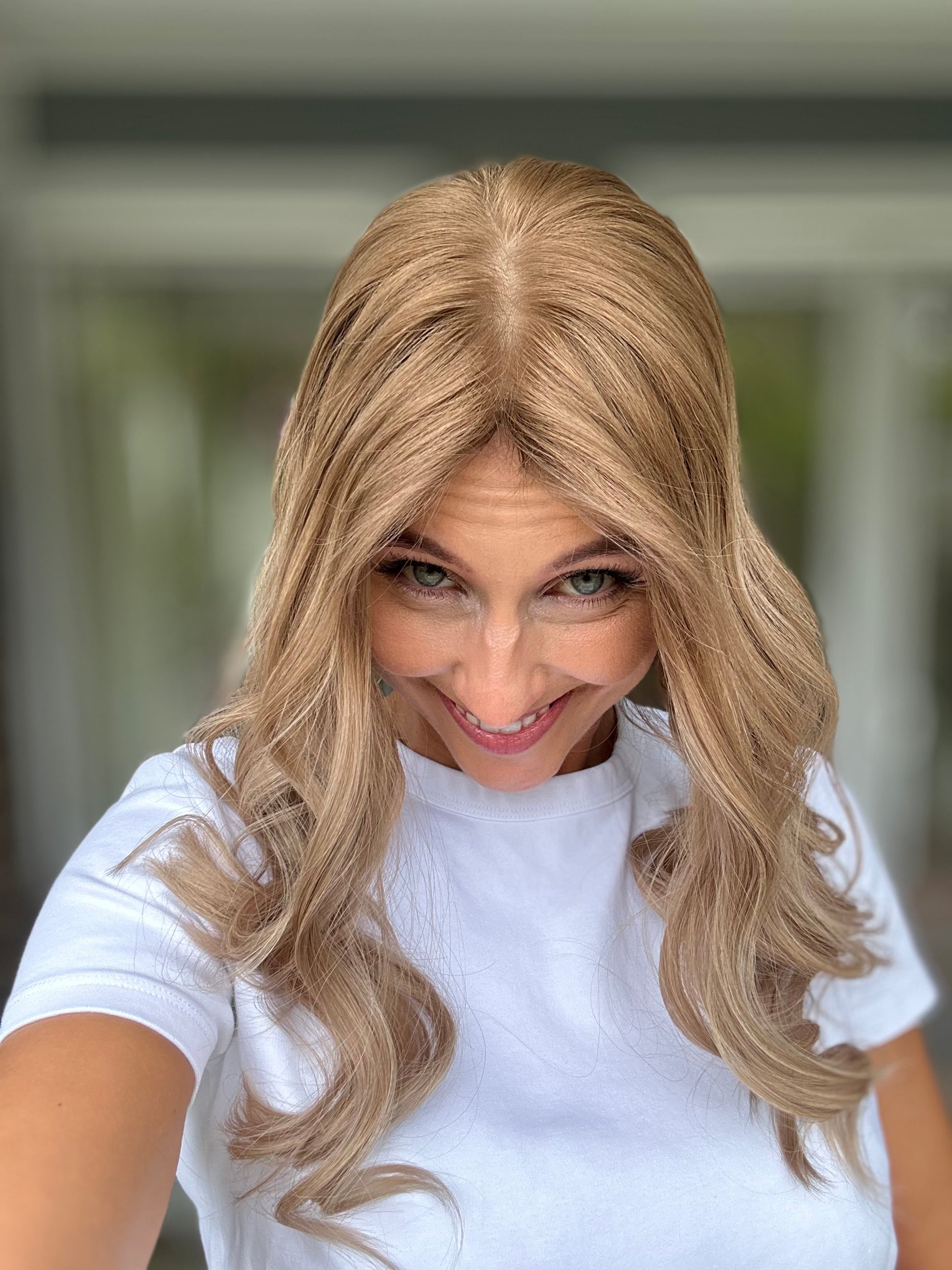 Bild zeigt attraktive Frau, die ihren Kopf leicht beugt, sodass blonder Haaransatz sichtbar wird. Bild dient der Produktpräsentation eines Artikels in der Kategorie Topper/Perücken.
