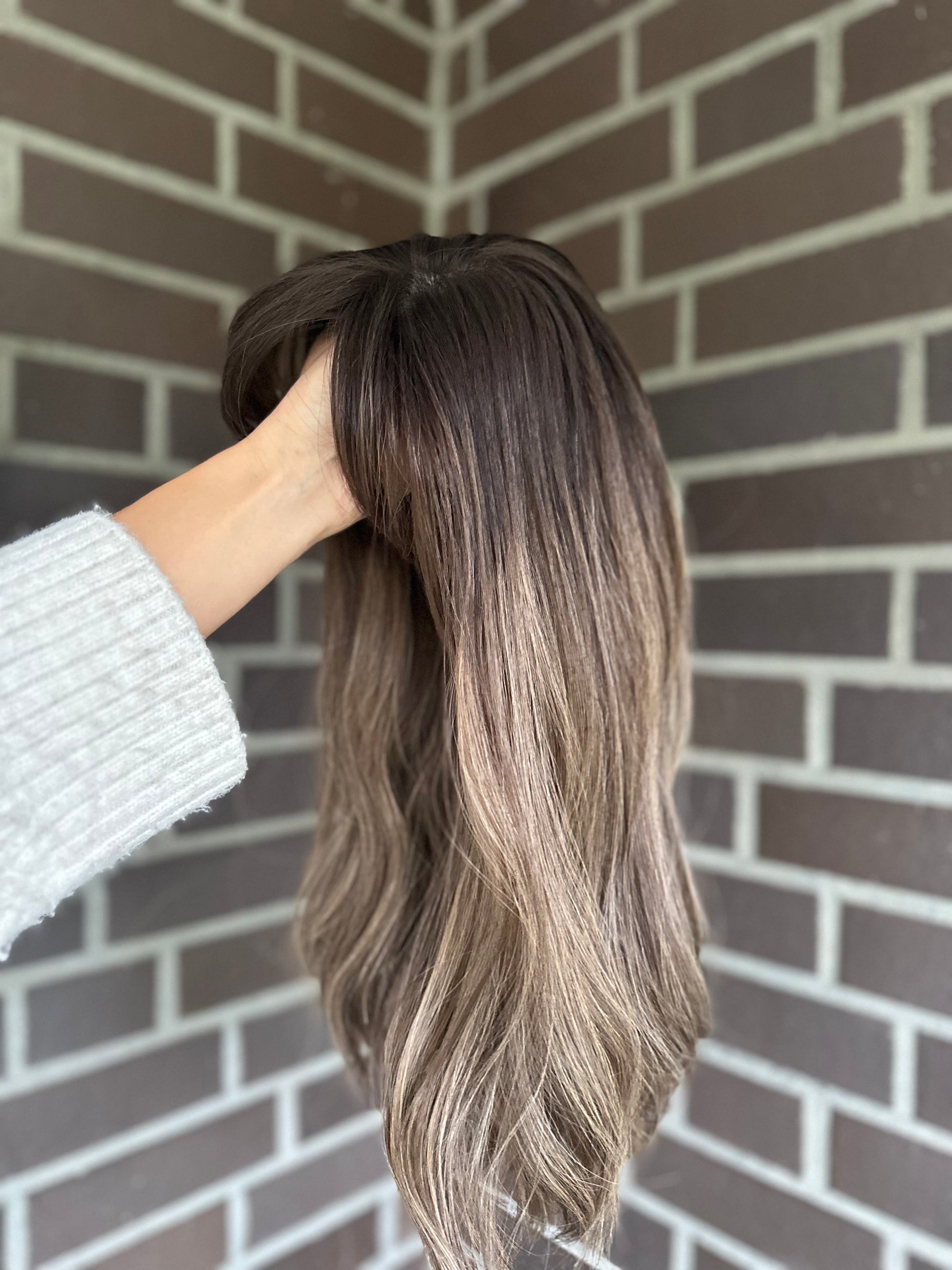 Bild zeigt blondes Echthaarteil, das seitlich ins Bild gehalten wird. Bild dient der Produktpräsentation eines Artikels in der Kategorie Topper/Perücken.