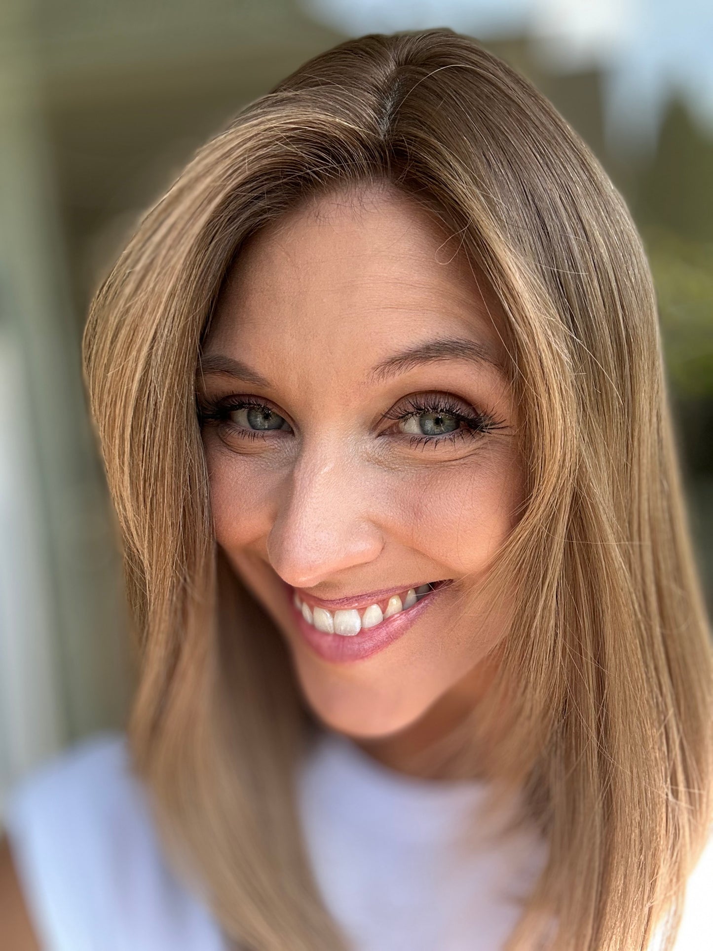 Bild zeigt attraktive Frau, die ihren Kopf leicht beugt, sodass blonder Haaransatz sichtbar wird. Bild dient der Produktpräsentation eines Artikels in der Kategorie Topper/Perücken.