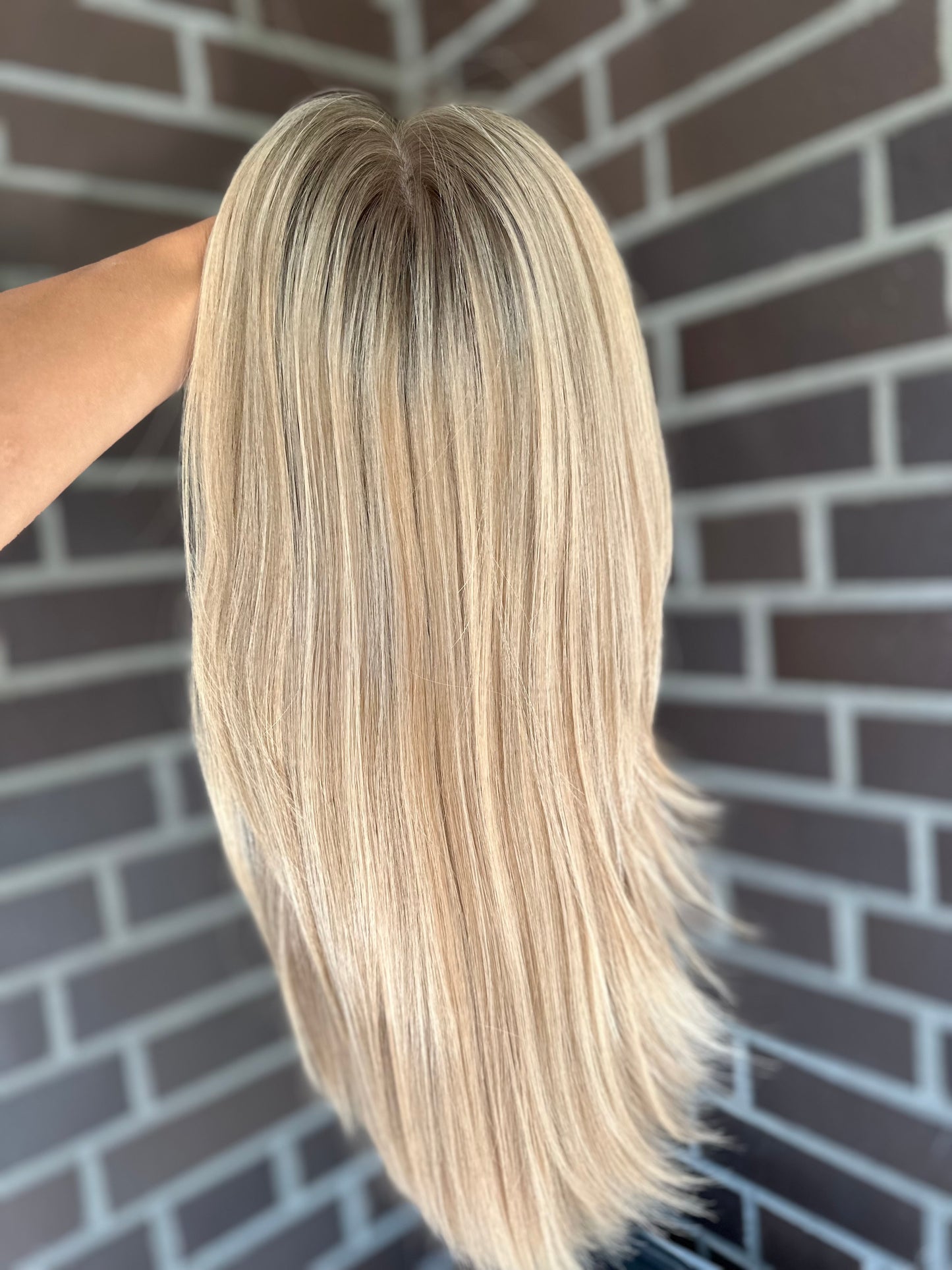 Bild zeigt blondes Echthaarteil, das frontal ins Bild gehalten wird. Bild dient der Produktpräsentation eines Artikels in der Kategorie Topper/Perücken.