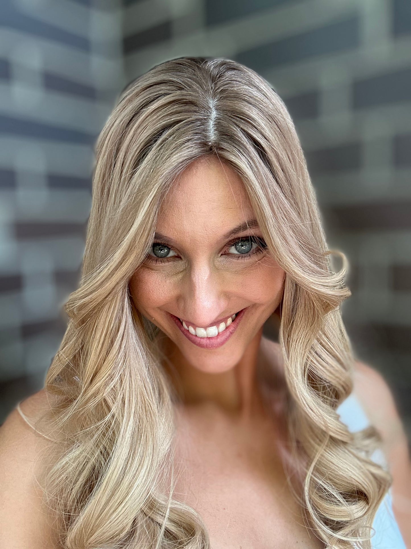 Bild zeigt attraktive Frau, die ihren Kopf leicht beugt, sodass blonder Haaransatz sichtbar wird. Bild dient der Produktpräsentation eines Artikels in der Kategorie Topper/Perücken.