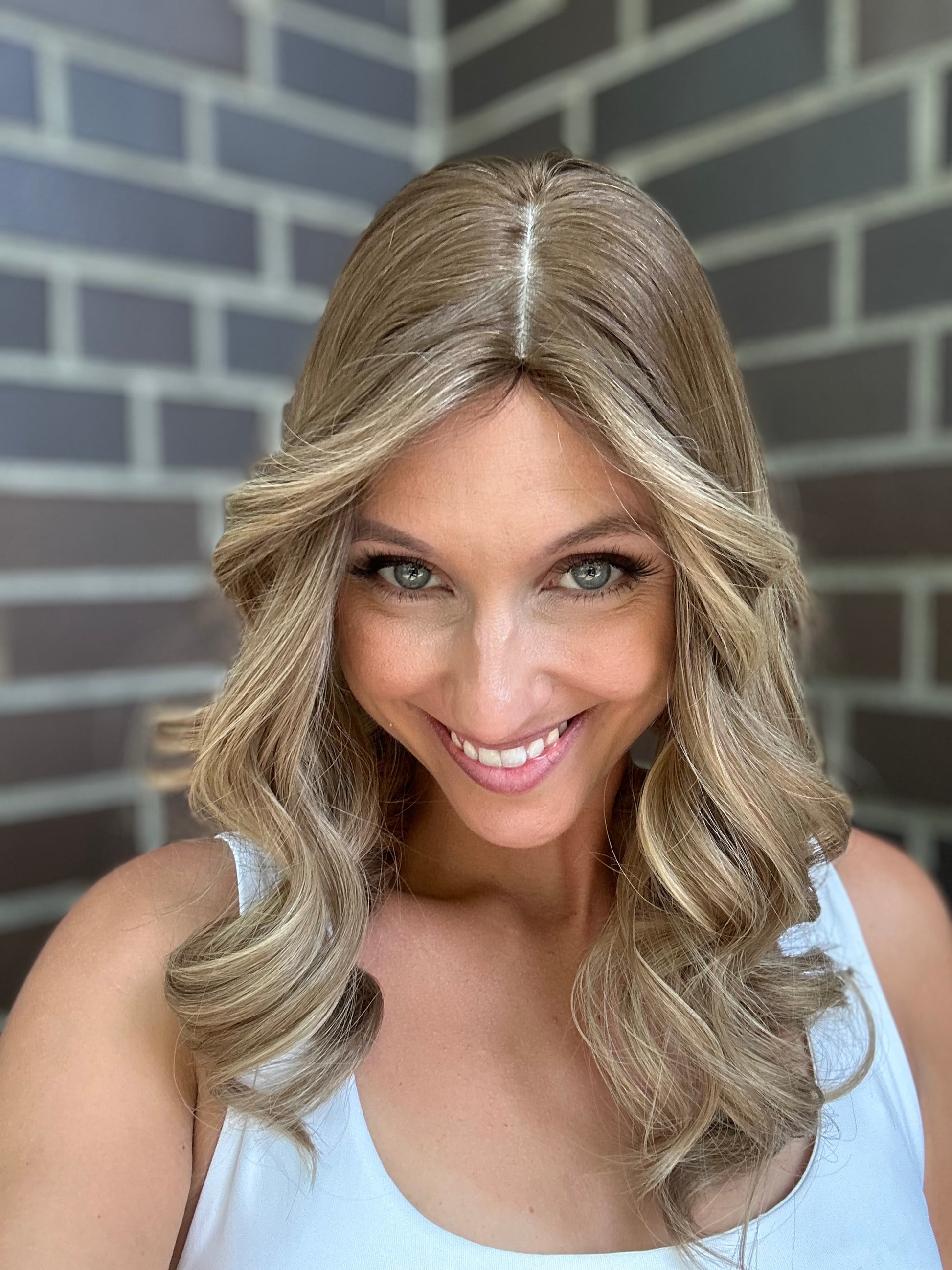 Bild zeigt attraktive Frau, die ihren Kopf leicht beugt, sodass blonder Haaransatz sichtbar wird. Bild dient der Produktpräsentation eines Artikels in der Kategorie Topper/Perücken.