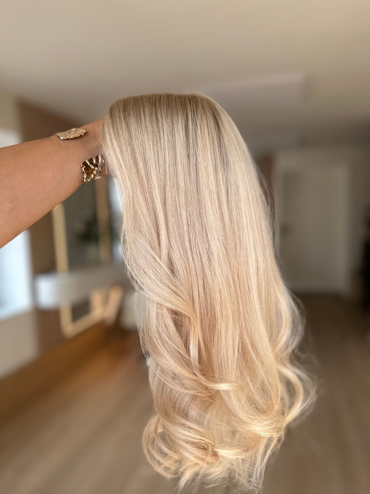Bild zeigt blondes Echthaarteil, das seitlich ins Bild gehalten wird. Bild dient der Produktpräsentation eines Artikels in der Kategorie Topper/Perücken.