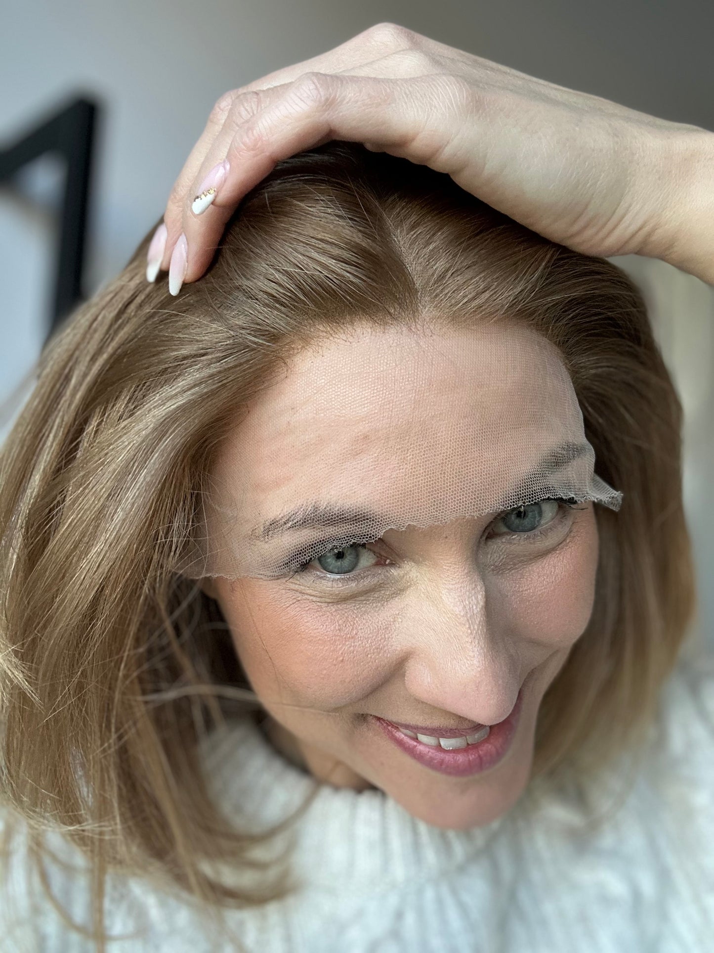 Bild zeigt attraktive Frau, die ihren Kopf leicht beugt, sodass blonder Haaransatz sichtbar wird. Bild dient der Produktpräsentation eines Artikels in der Kategorie Topper/Perücken.
