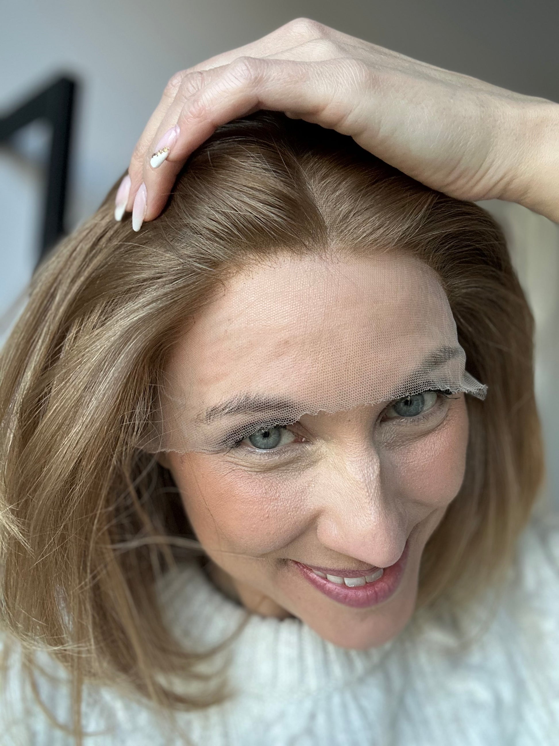 Bild zeigt attraktive Frau, die ihren Kopf leicht beugt, sodass blonder Haaransatz sichtbar wird. Bild dient der Produktpräsentation eines Artikels in der Kategorie Topper/Perücken.