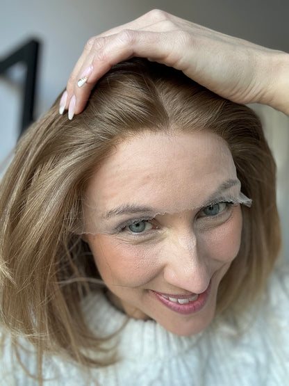 Bild zeigt attraktive Frau, die ihren Kopf leicht beugt, sodass blonder Haaransatz sichtbar wird. Bild dient der Produktpräsentation eines Artikels in der Kategorie Topper/Perücken.