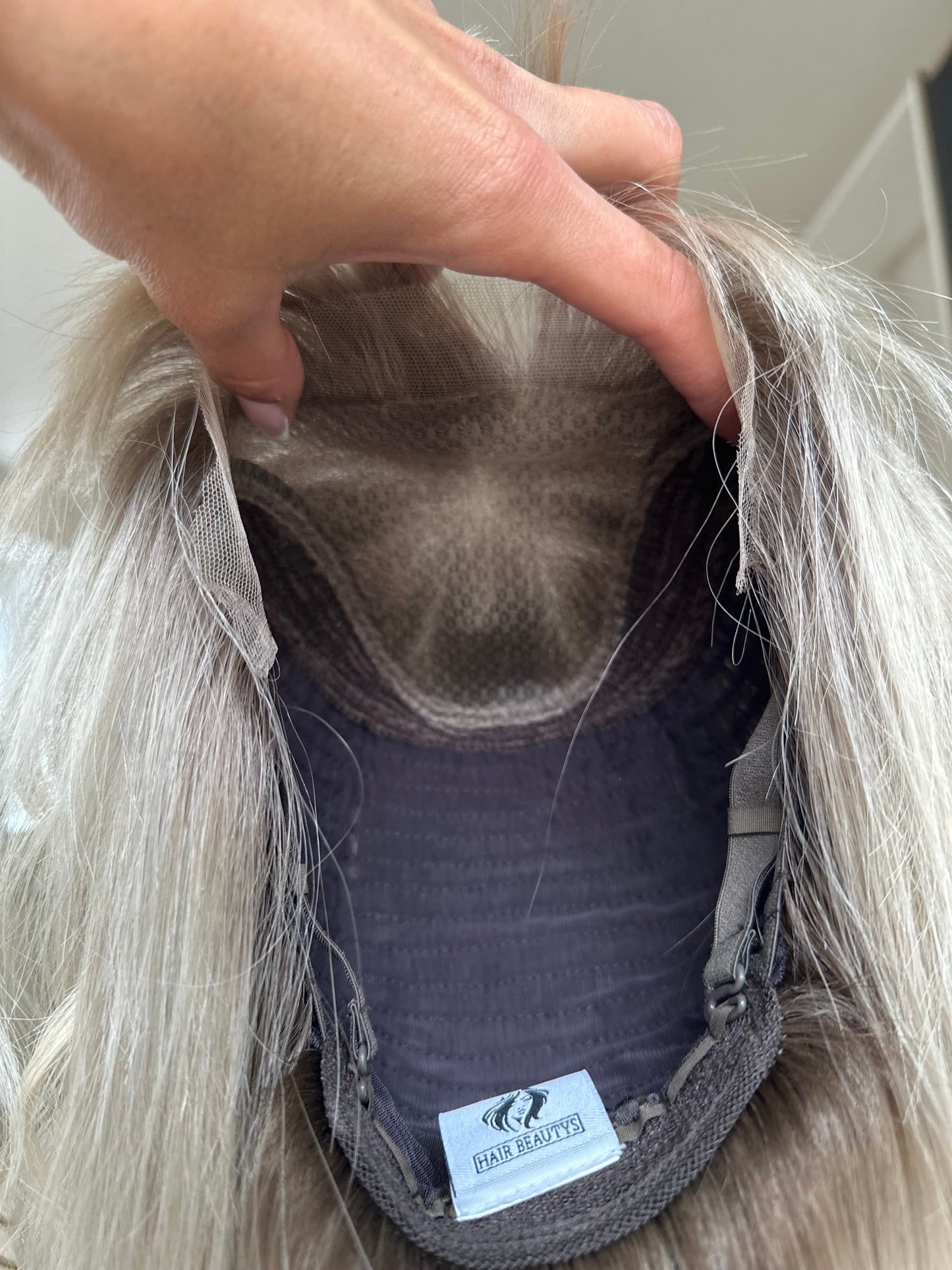 Bild zeigt blondes Echthaarteil, dessen Haaransatz  ins Bild gehalten wird. Bild dient der Produktpräsentation in der Kategorie Topper/Perücken.