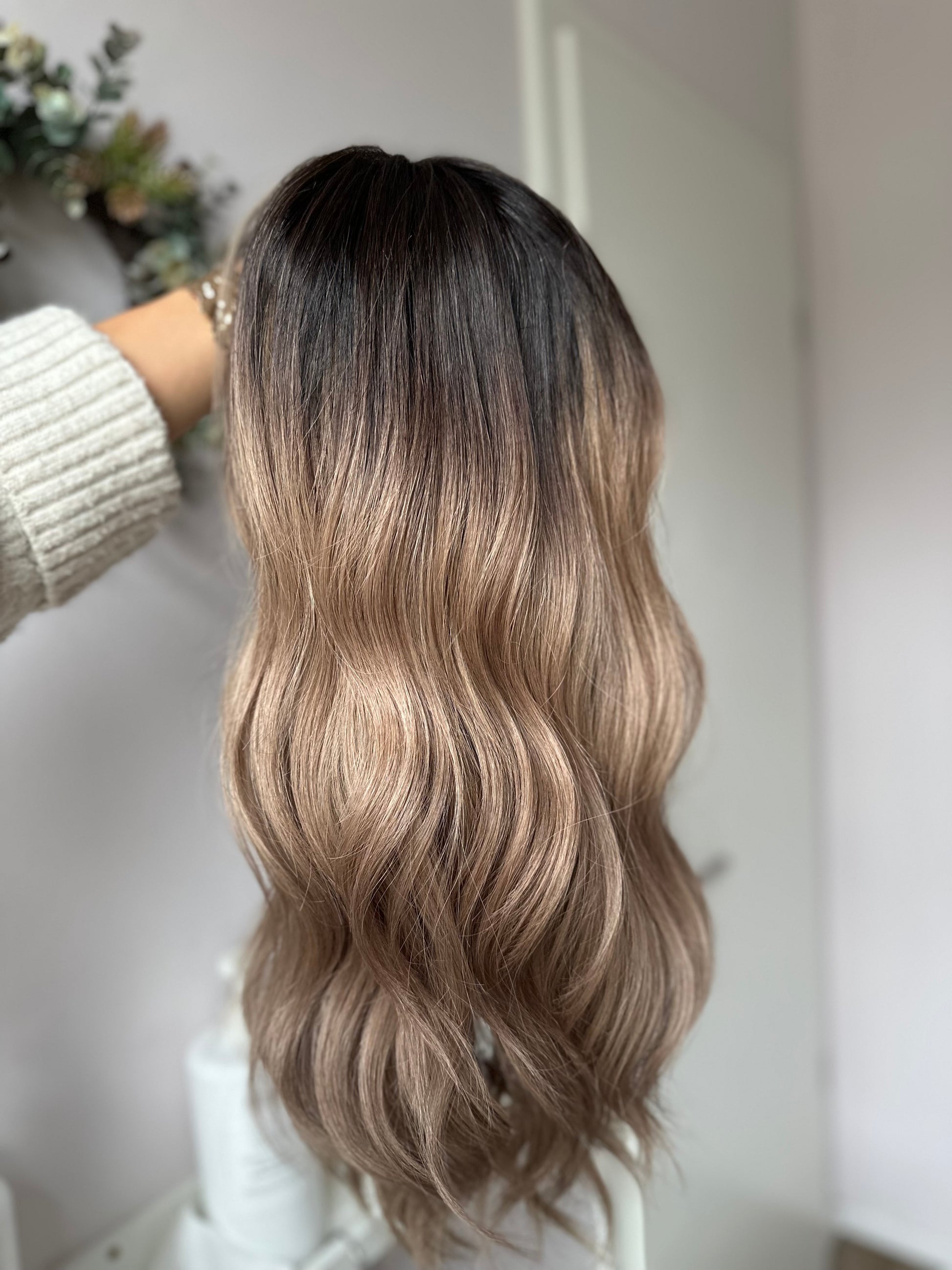 Bild zeigt blondes Echthaarteil, das frontal ins Bild gehalten wird. Bild dient der Produktpräsentation eines Artikels in der Kategorie Topper/Perücken.