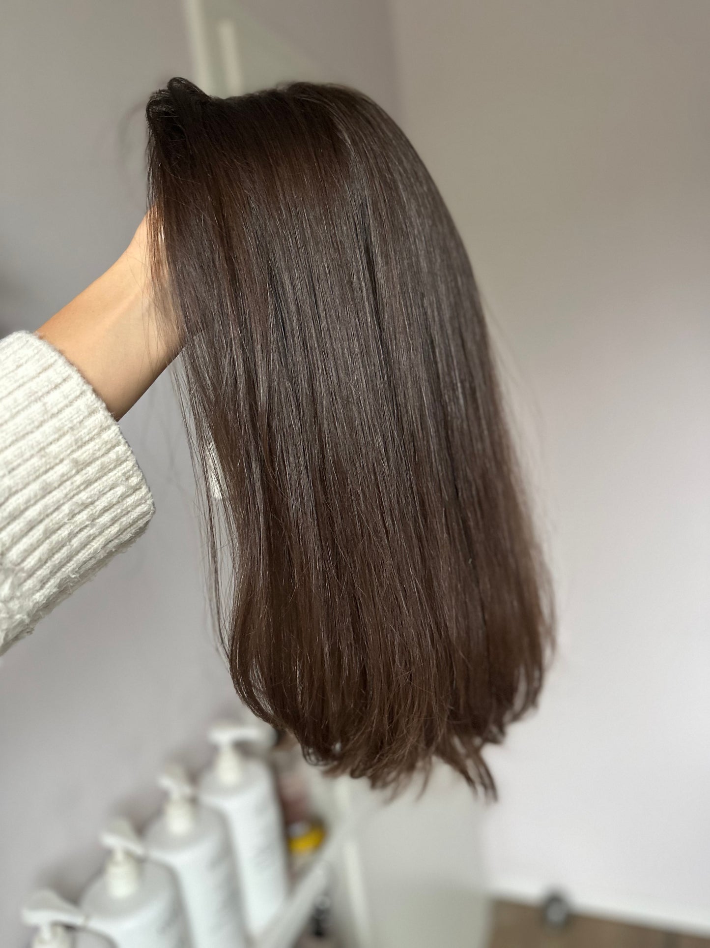 Bild zeigt braunes Echthaarteil, das seitlich ins Bild gehalten wird. Bild dient der Produktpräsentation in der Kategorie Topper/Perücken.