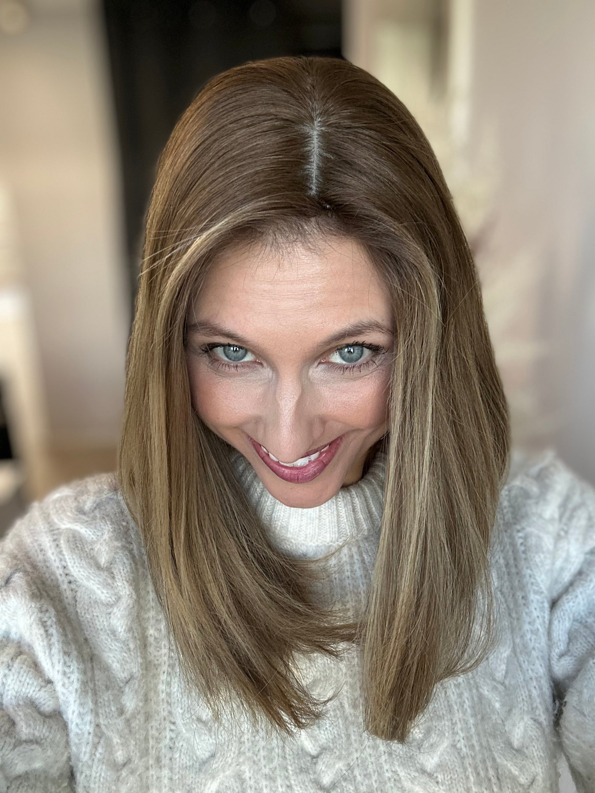 Bild zeigt attraktive Frau, die ihren Kopf leicht beugt, sodass brauner Haaransatz sichtbar wird. Bild dient der Produktpräsentation eines Artikels in der Kategorie Topper/Perücken.