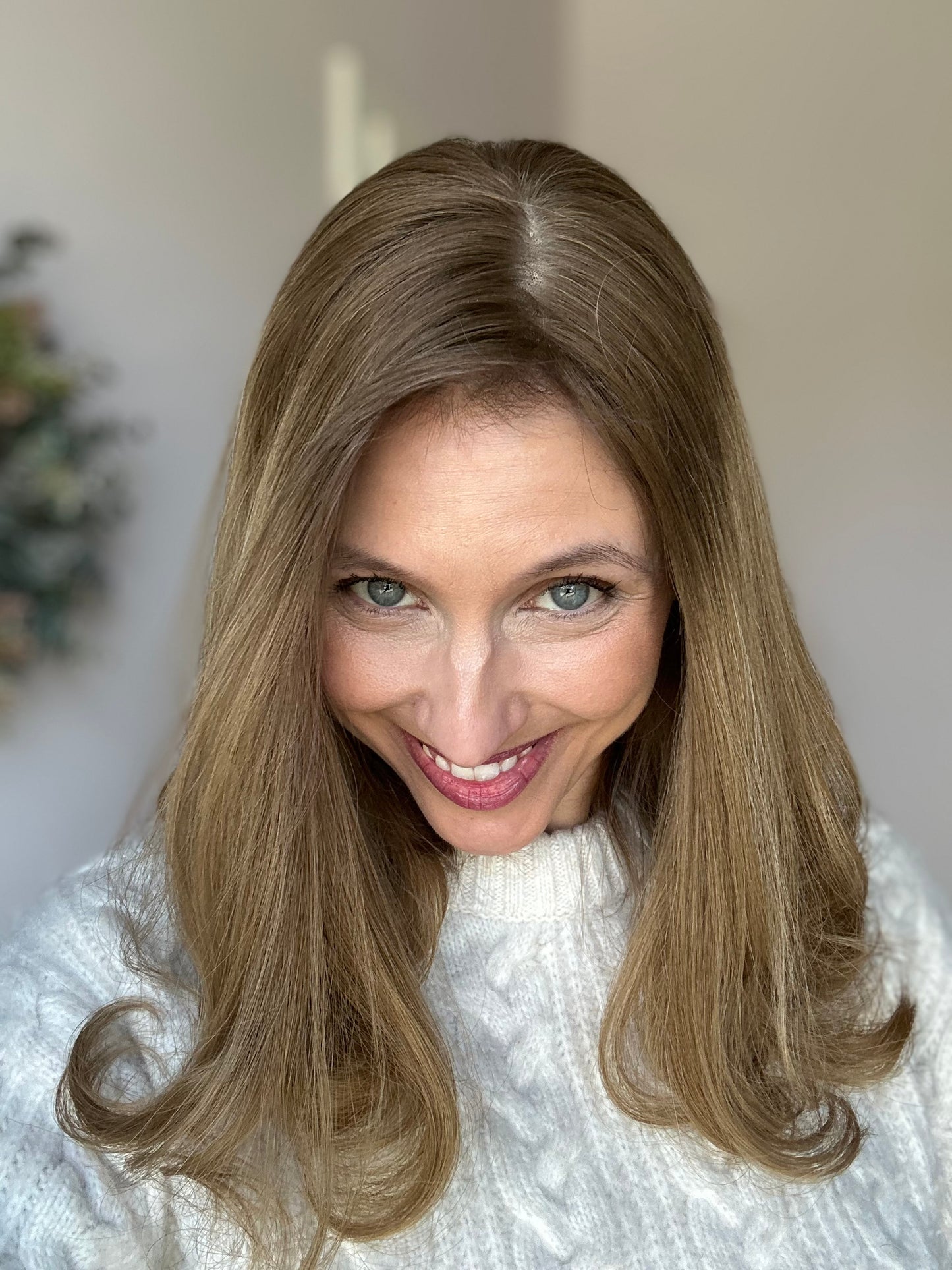 Bild zeigt attraktive Frau, die ihren Kopf leicht beugt, sodass blonder Haaransatz sichtbar wird. Bild dient der Produktpräsentation eines Artikels in der Kategorie Topper/Perücken.