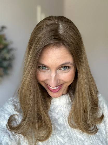 Bild zeigt attraktive Frau, die ihren Kopf leicht beugt, sodass blonder Haaransatz sichtbar wird. Bild dient der Produktpräsentation eines Artikels in der Kategorie Topper/Perücken.