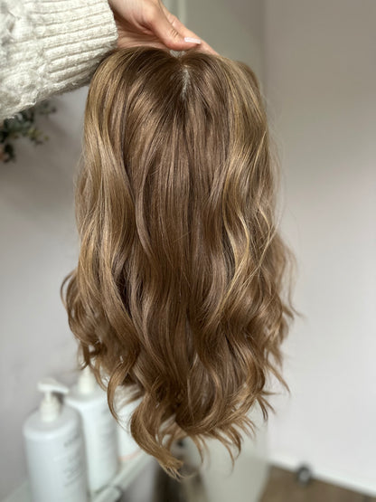 Bild zeigt braunes Echthaarteil, das frontal ins Bild gehalten wird. Bild dient der Produktpräsentation eines Artikels  in der Kategorie Topper/Perücken.