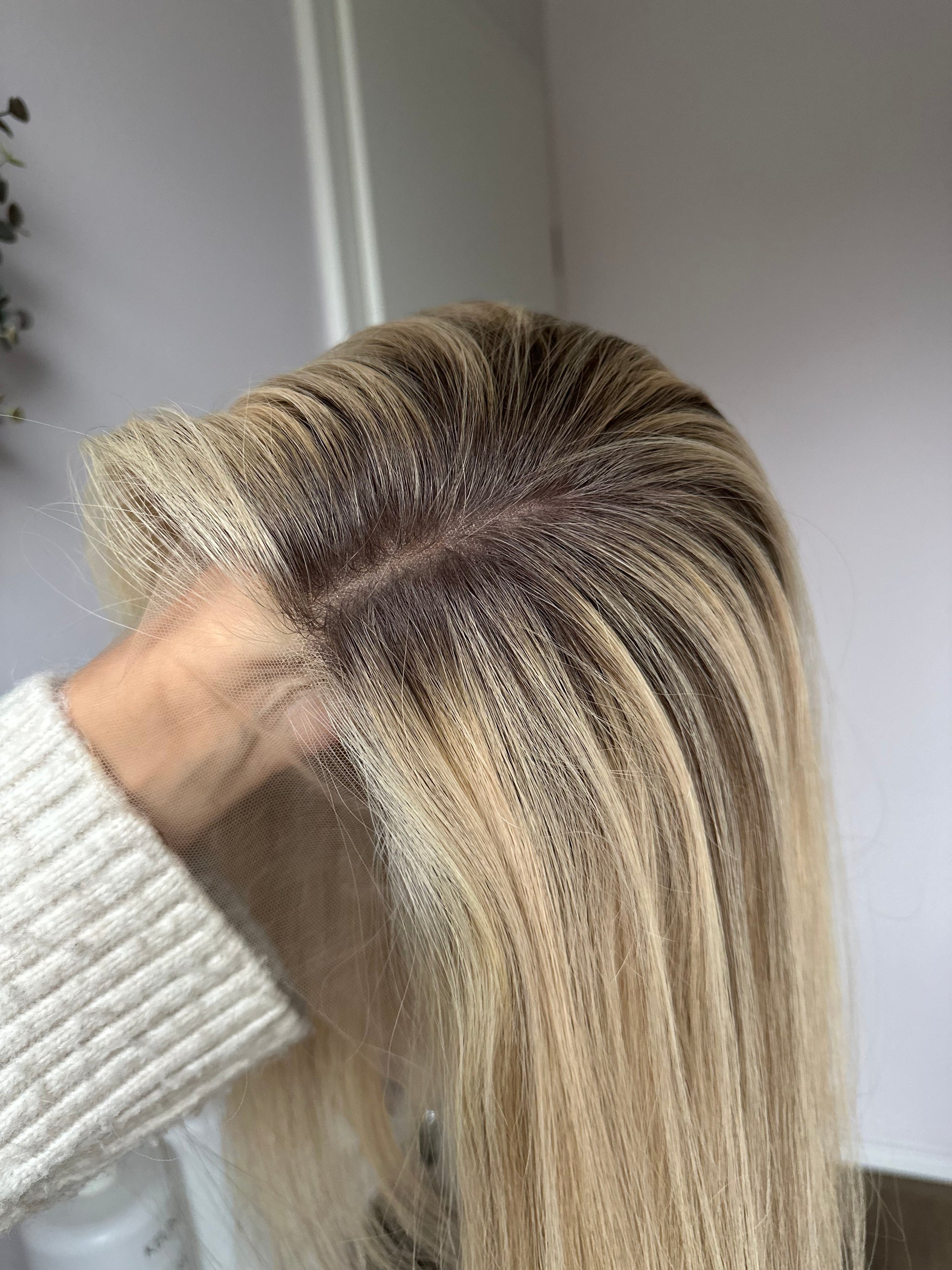 Bild zeigt blondes Echthaarteil, dessen Haaransatz  ins Bild gehalten wird. Bild dient der Produktpräsentation in der Kategorie Topper/Perücken.