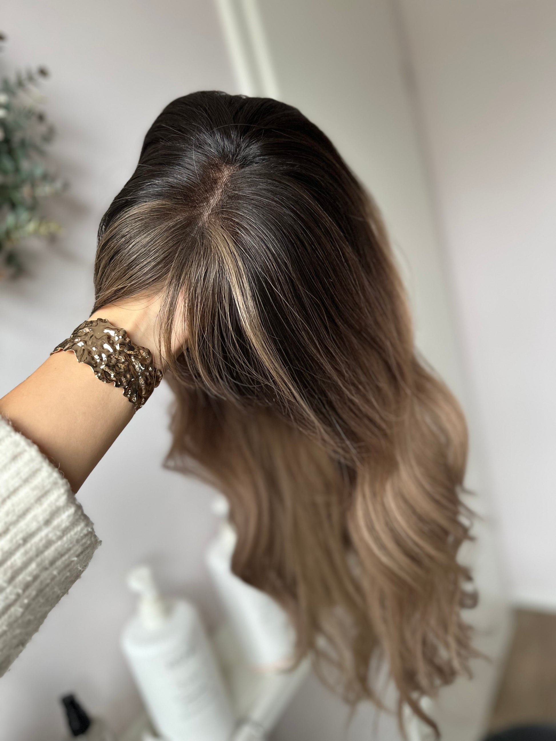 Bild zeigt blondes Echthaarteil, das seitlich ins Bild gehalten wird. Bild dient der Produktpräsentation eines Artikels in der Kategorie Topper/Perücken.