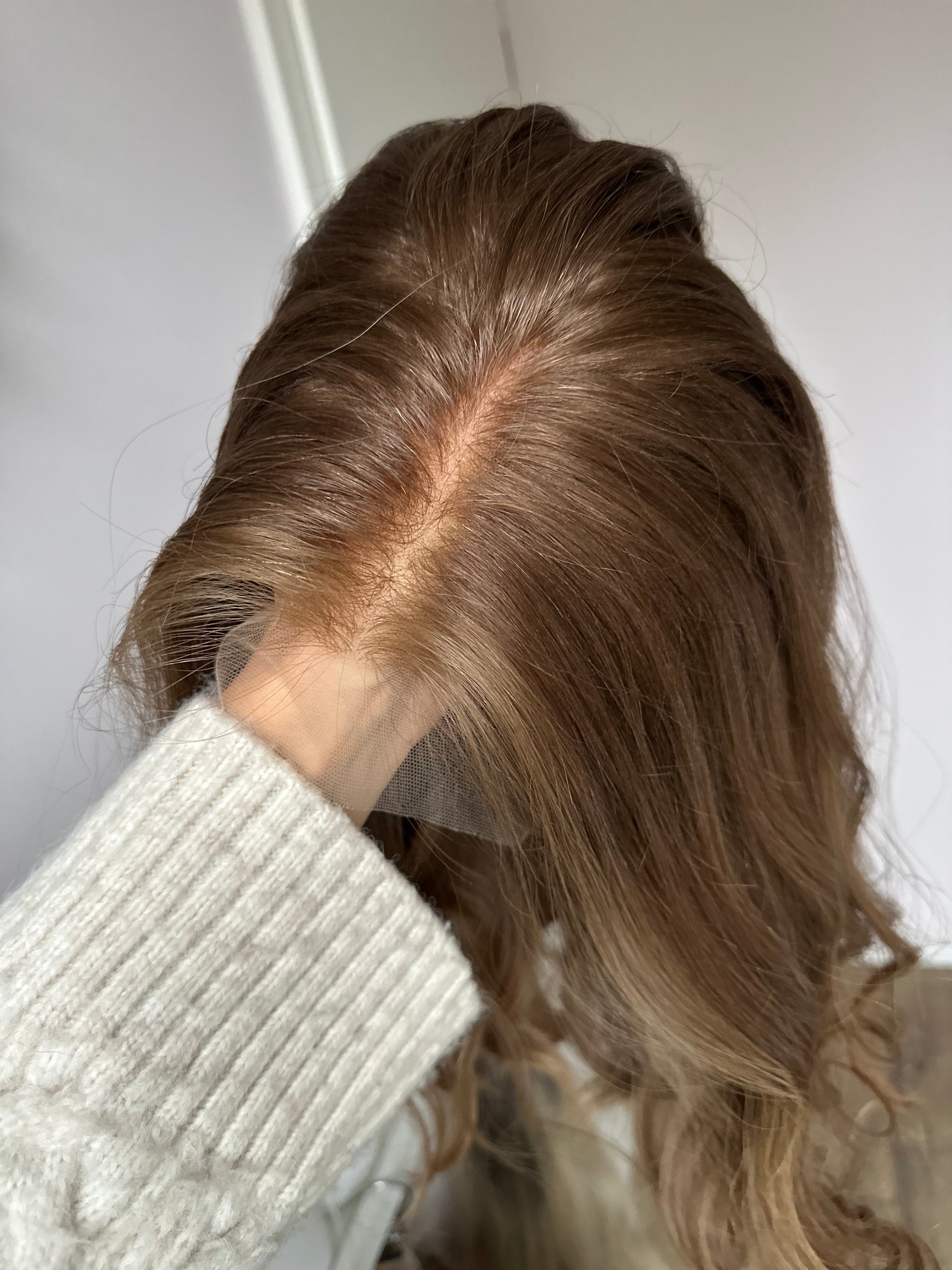 Bild zeigt braunes Echthaarteil, dessen Haaransatz  ins Bild gehalten wird. Bild dient der Produktpräsentation in der Kategorie Topper/Perücken.