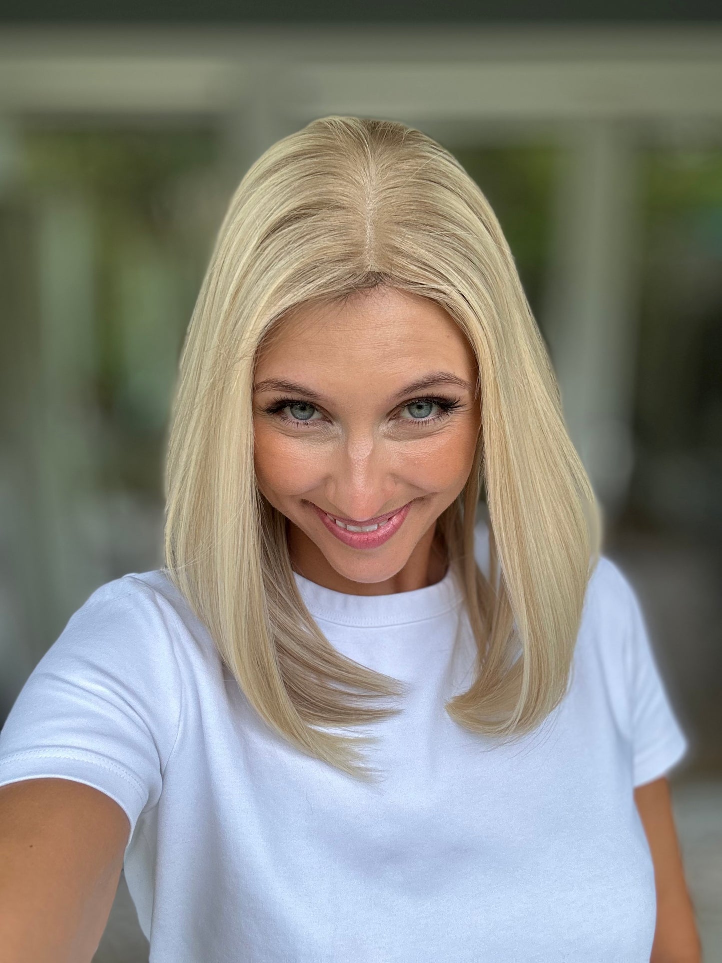 Bild zeigt attraktive Frau, die ihren Kopf leicht beugt, sodass blonder Haaransatz sichtbar wird. Bild dient der Produktpräsentation eines Artikels in der Kategorie Topper/Perücken.
