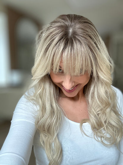 Bild zeigt attraktive Frau, die ihren Kopf leicht beugt, sodass blonder Haaransatz sichtbar wird. Bild dient der Produktpräsentation eines Artikels in der Kategorie Topper/Perücken.