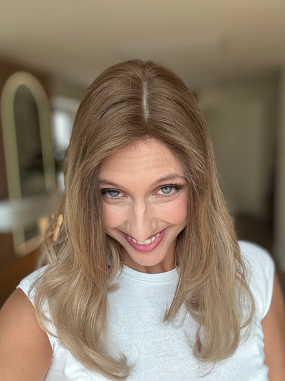 Bild zeigt attraktive Frau, die ihren Kopf leicht beugt, sodass blonder Haaransatz sichtbar wird. Bild dient der Produktpräsentation eines Artikels in der Kategorie Topper/Perücken.