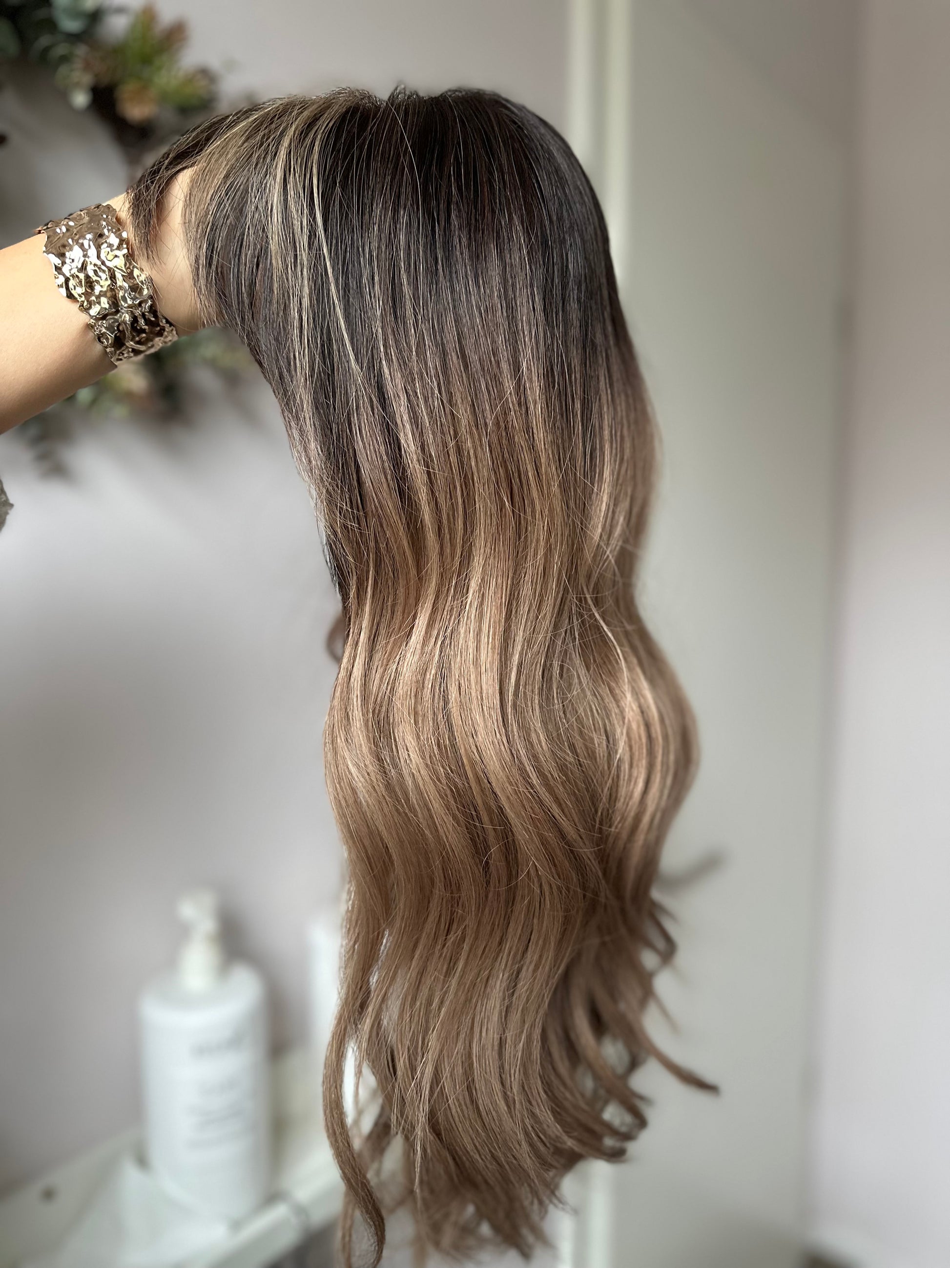 Bild zeigt blondes Echthaarteil, das seitlich ins Bild gehalten wird. Bild dient der Produktpräsentation eines Artikels in der Kategorie Topper/Perücken.