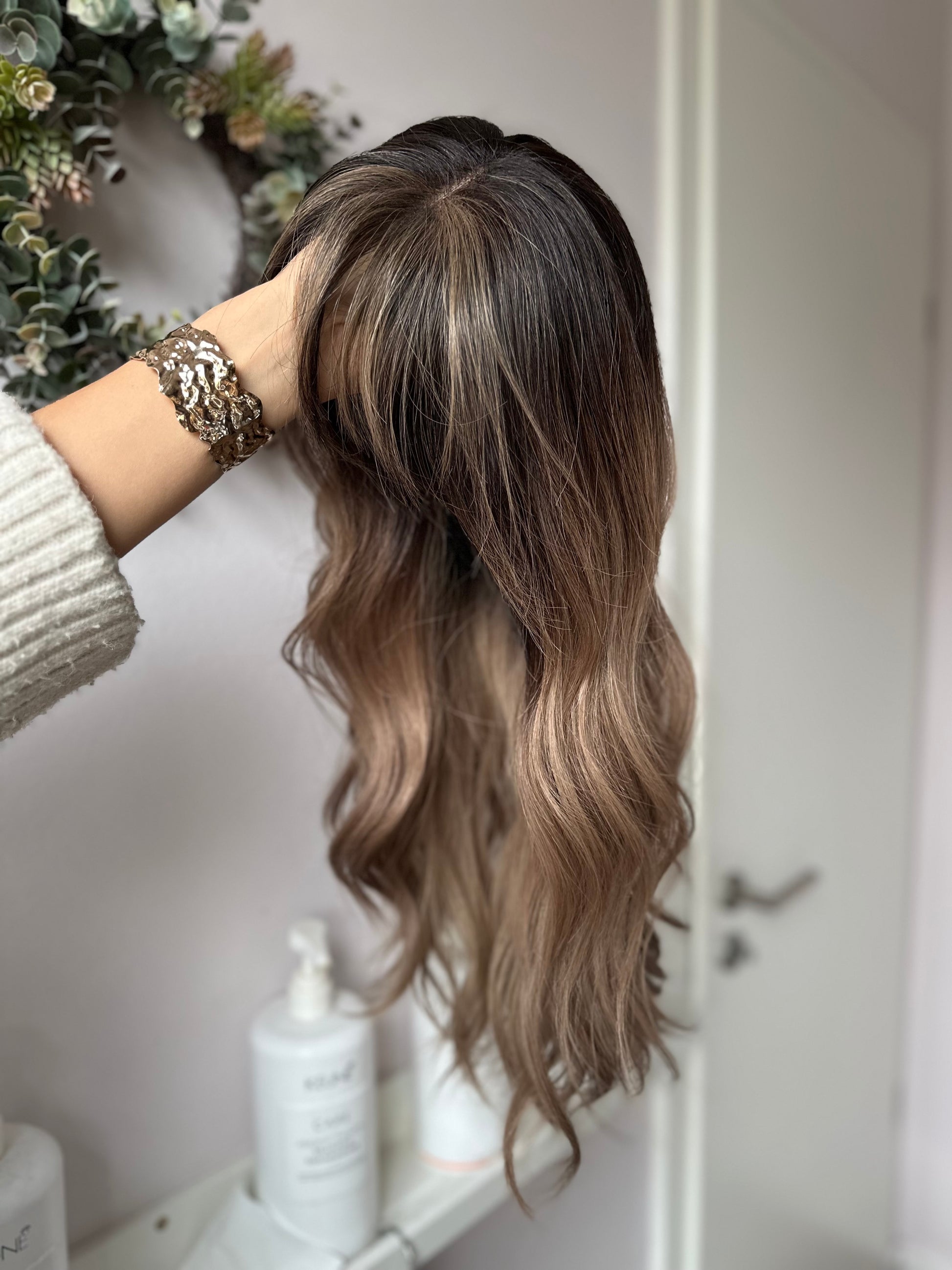 Bild zeigt blondes Echthaarteil, das seitlich ins Bild gehalten wird. Bild dient der Produktpräsentation eines Artikels in der Kategorie Topper/Perücken.