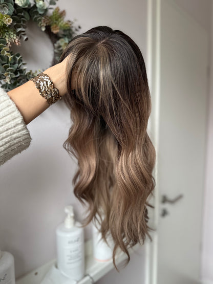 Bild zeigt blondes Echthaarteil, das seitlich ins Bild gehalten wird. Bild dient der Produktpräsentation eines Artikels in der Kategorie Topper/Perücken.