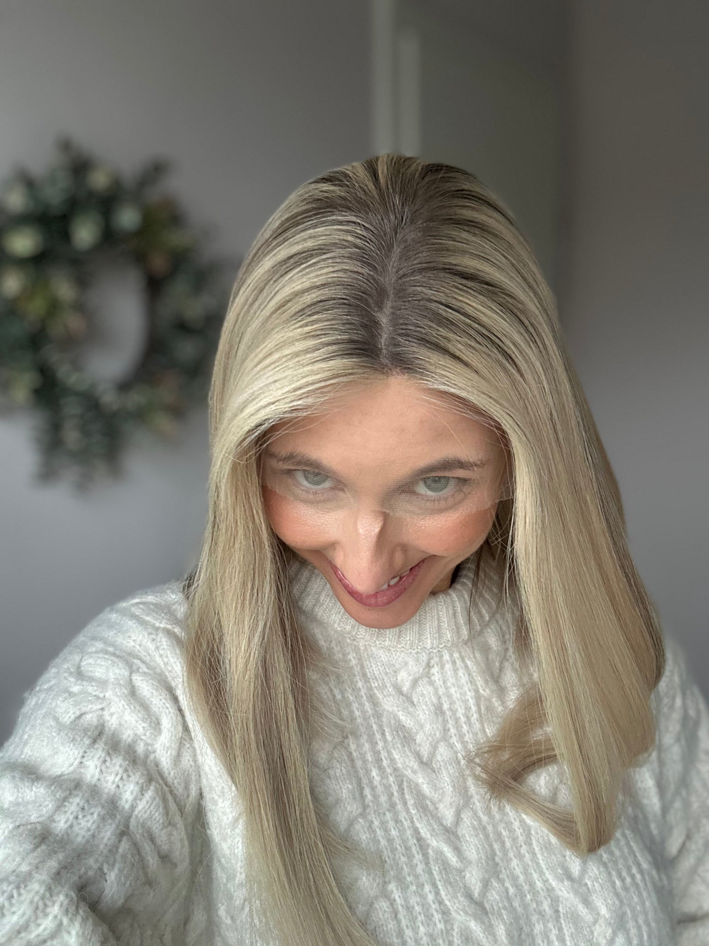 Bild zeigt attraktive Frau, die ihren Kopf leicht beugt, sodass blonder Haaransatz sichtbar wird. Bild dient der Produktpräsentation eines Artikels in der Kategorie Topper/Perücken.