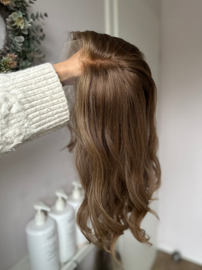 Bild zeigt braunes Echthaarteil, das seitlich ins Bild gehalten wird. Bild dient der Produktpräsentation in der Kategorie Topper/Perücken.