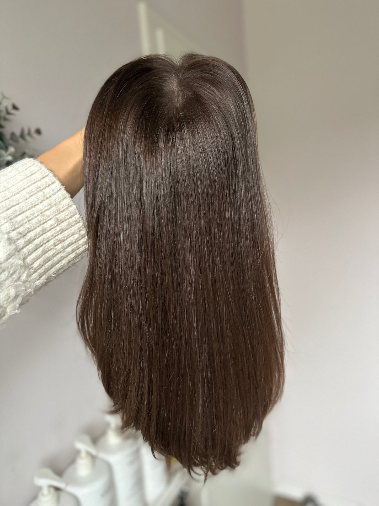 Bild zeigt braunes Echthaarteil, das frontal ins Bild gehalten wird. Bild dient der Produktpräsentation eines Artikels  in der Kategorie Topper/Perücken.