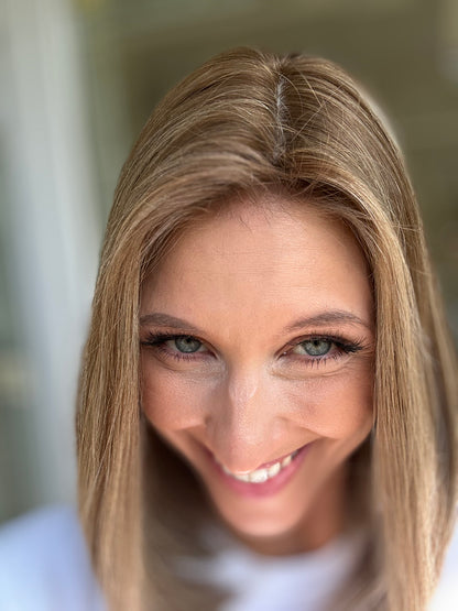 Bild zeigt attraktive Frau, die ihren Kopf leicht beugt, sodass blonder Haaransatz sichtbar wird. Bild dient der Produktpräsentation eines Artikels in der Kategorie Topper/Perücken.
