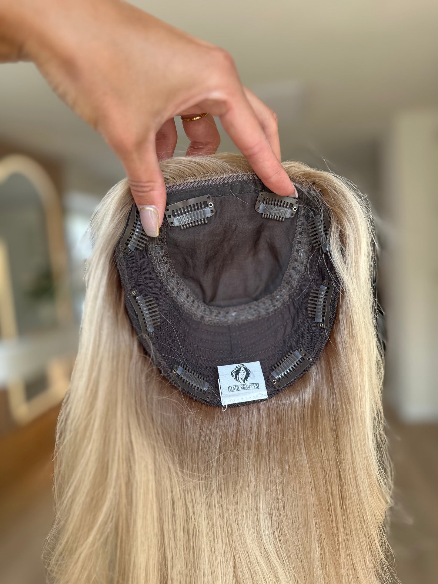 blondes Echthaarteil wird frontal im Video gezeigt. Foto dient der Produktpräsentation eines Artikels in der Kategorie Topper/Perücken.