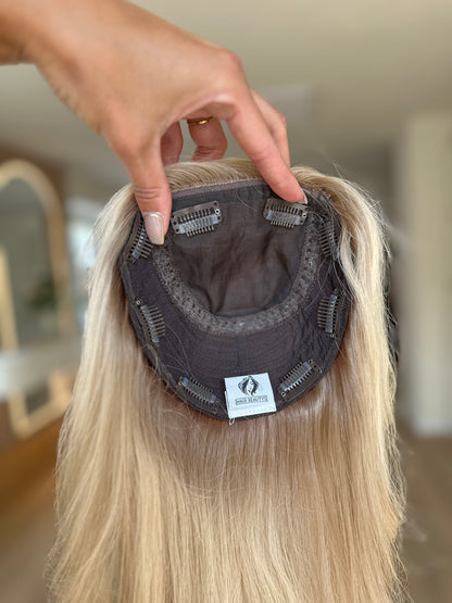 blondes Echthaarteil wird frontal im Video gezeigt. Foto dient der Produktpräsentation eines Artikels in der Kategorie Topper/Perücken.