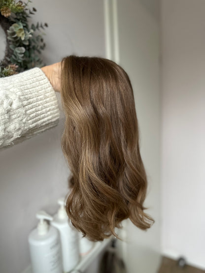 Bild zeigt braunes Echthaarteil, das seitlich ins Bild gehalten wird. Bild dient der Produktpräsentation in der Kategorie Topper/Perücken.