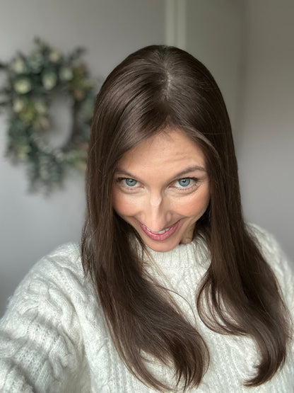 Bild zeigt attraktive Frau, die ihren Kopf leicht beugt, sodass brauner Haaransatz sichtbar wird. Bild dient der Produktpräsentation eines Artikels in der Kategorie Topper/Perücken.