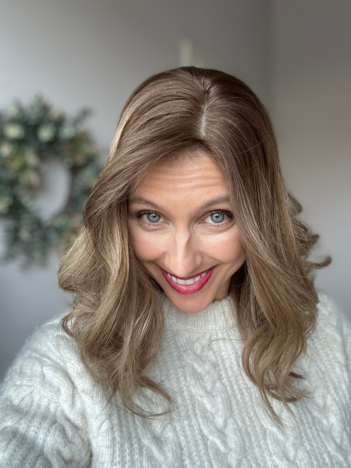 Bild zeigt attraktive Frau, die ihren Kopf leicht beugt, sodass blonder Haaransatz sichtbar wird. Bild dient der Produktpräsentation eines Artikels in der Kategorie Topper/Perücken.