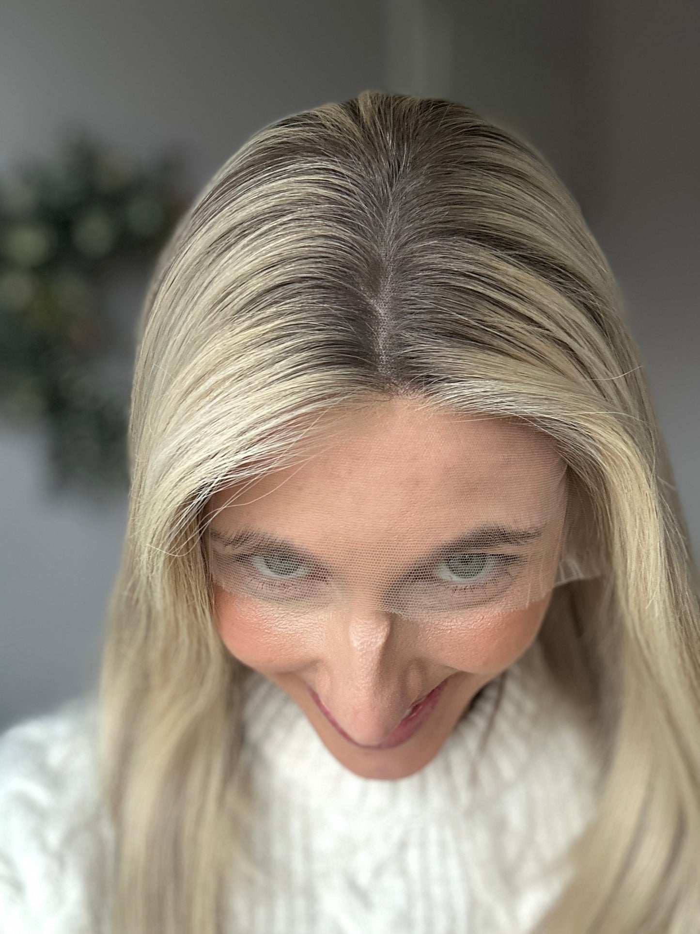 Bild zeigt attraktive Frau, die ihren Kopf leicht beugt, sodass blonder Haaransatz sichtbar wird. Bild dient der Produktpräsentation eines Artikels in der Kategorie Topper/Perücken.