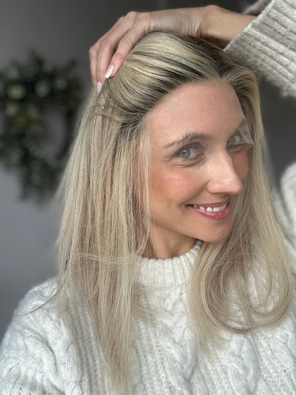 Bild zeigt attraktive Frau, die ihren Kopf leicht beugt, sodass blonder Haaransatz sichtbar wird. Bild dient der Produktpräsentation eines Artikels in der Kategorie Topper/Perücken.