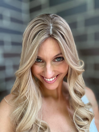 Bild zeigt attraktive Frau, die ihren Kopf leicht beugt, sodass blonder Haaransatz sichtbar wird. Bild dient der Produktpräsentation eines Artikels in der Kategorie Topper/Perücken.