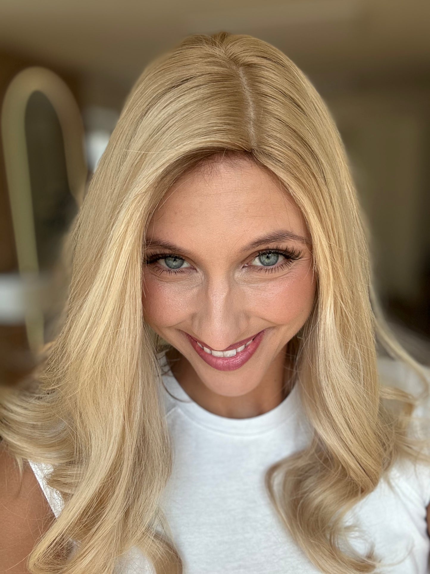 Bild zeigt attraktive Frau, die ihren Kopf leicht beugt, sodass blonder Haaransatz sichtbar wird. Bild dient der Produktpräsentation eines Artikels in der Kategorie Topper/Perücken.