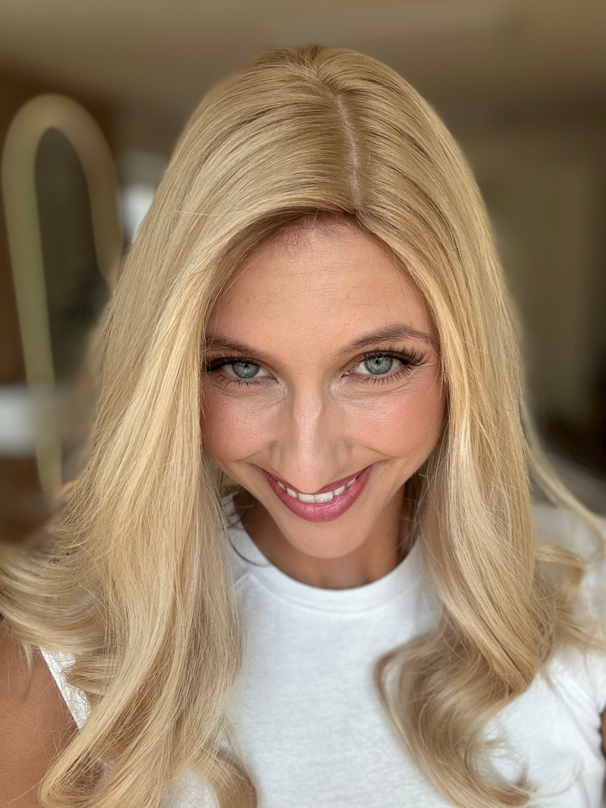 Bild zeigt attraktive Frau, die ihren Kopf leicht beugt, sodass blonder Haaransatz sichtbar wird. Bild dient der Produktpräsentation eines Artikels in der Kategorie Topper/Perücken.