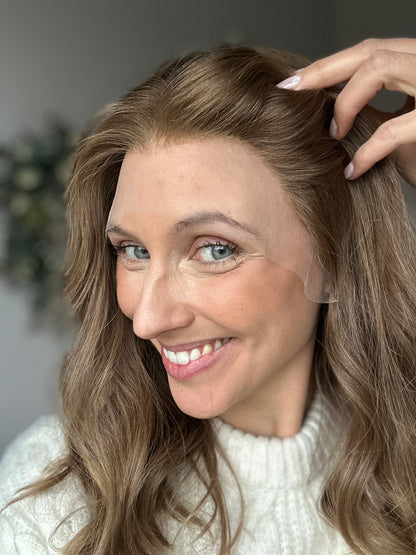 Bild zeigt braunes Echthaarteil, dessen Haaransatz  ins Bild gehalten wird. Bild dient der Produktpräsentation in der Kategorie Topper/Perücken.