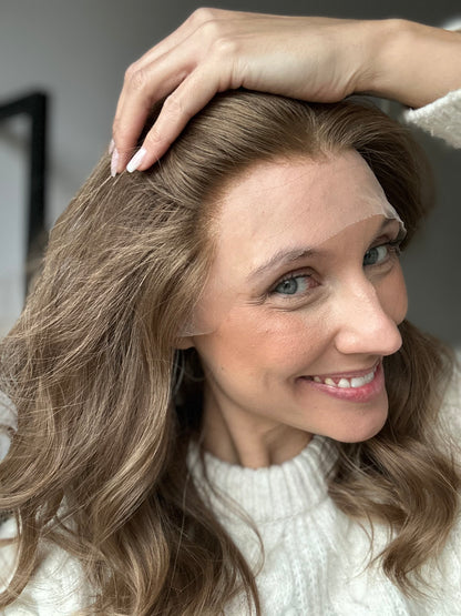 Bild zeigt braunes Echthaarteil, dessen Haaransatz  ins Bild gehalten wird. Bild dient der Produktpräsentation in der Kategorie Topper/Perücken.