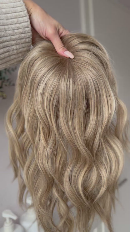 blondes Echthaarteil wird frontal im Video gezeigt. Video dient der Produktpräsentation eines Artikels in der Kategorie Topper/Perücken.